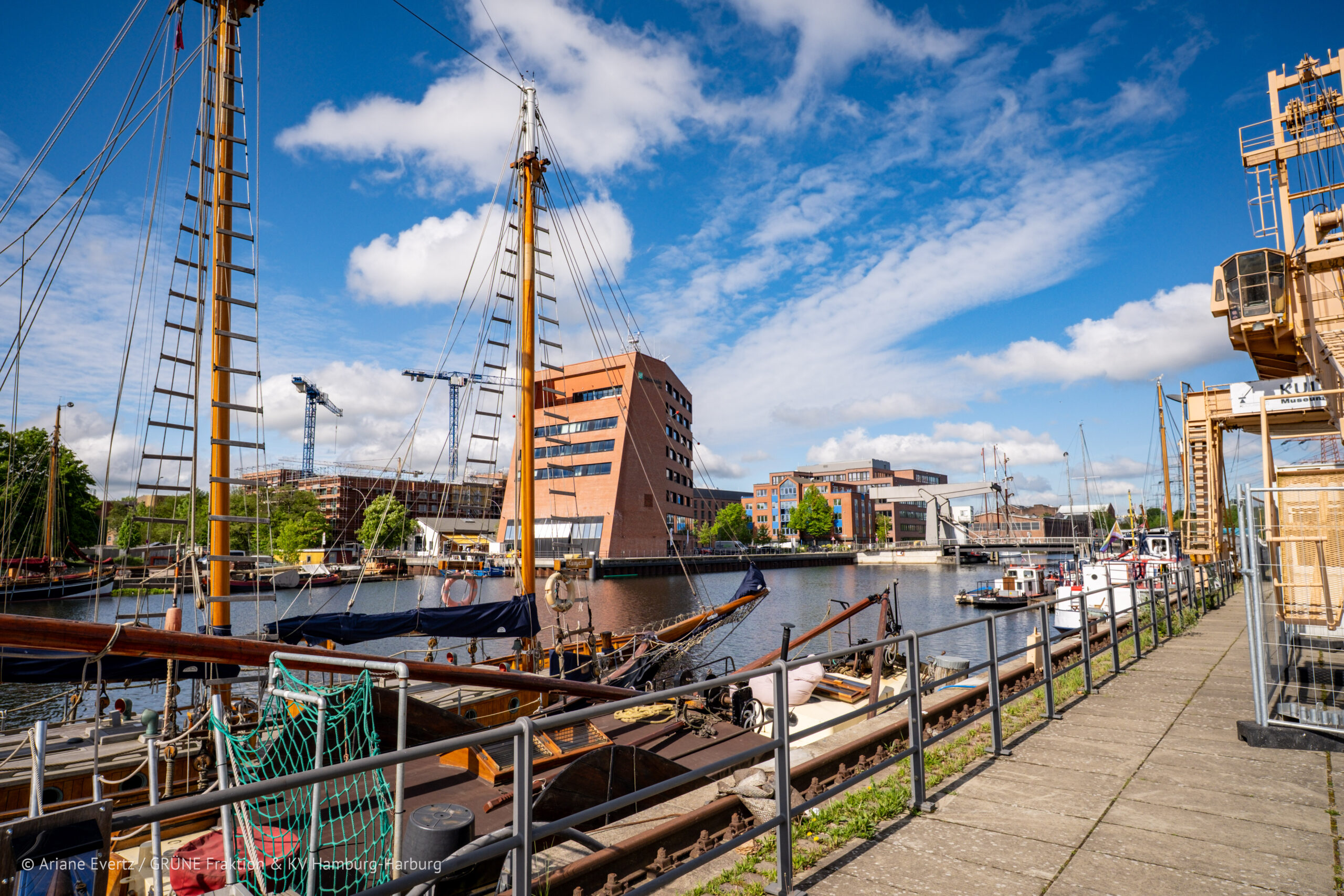 Der Harburger Binnenhafen mit einem Schiff im Vordergrund, das im Hafen liegt. Im Hintergrund sieht man moderne Gebäude des Binnenhafens aus rotem Klinker.